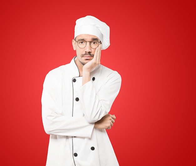 Cansado jovem chef fazendo um gesto de tédio
