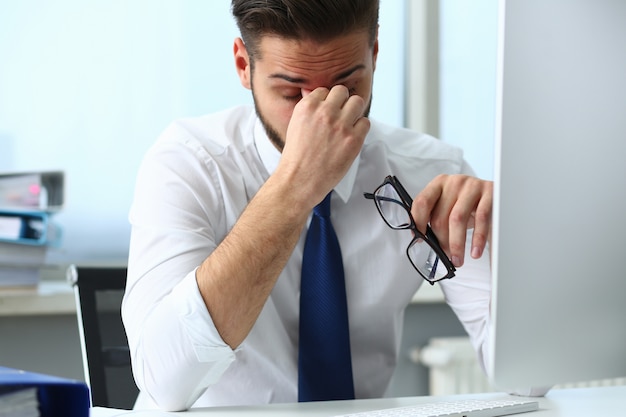 Cansado joven oficinista masajeando sus ojos