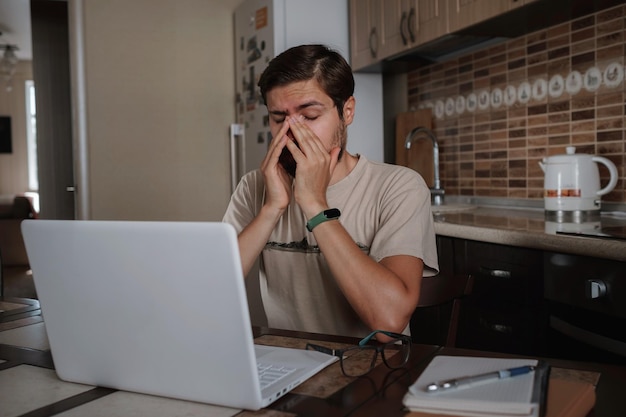 Cansado joven siente dolor vista cansada sosteniendo gafas frotando los ojos secos e irritados