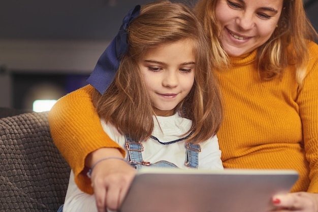 Cansado de leer las mismas historias aburridas a tus hijos Fotografía de una madre y su hija usando una tableta digital juntas