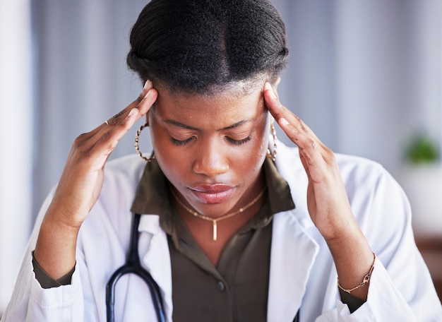 Cansado médico mulher negra e estresse com dor de cabeça no consultório da clínica e pensando com dor no trabalho Fadiga médica sobrecarregada e esgotamento no hospital preocupação ou ansiedade pela saúde mental no bem-estar