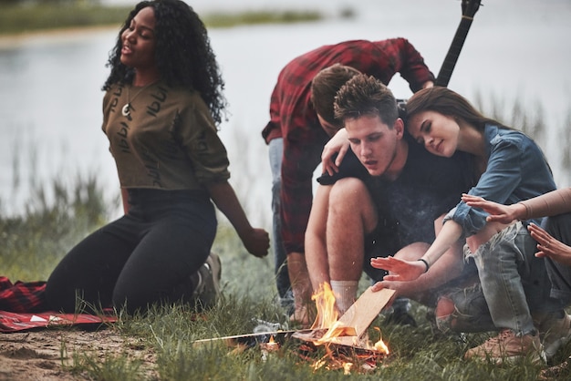 Foto cansado y somnoliento. grupo de personas tienen picnic en la playa. los amigos se divierten los fines de semana.