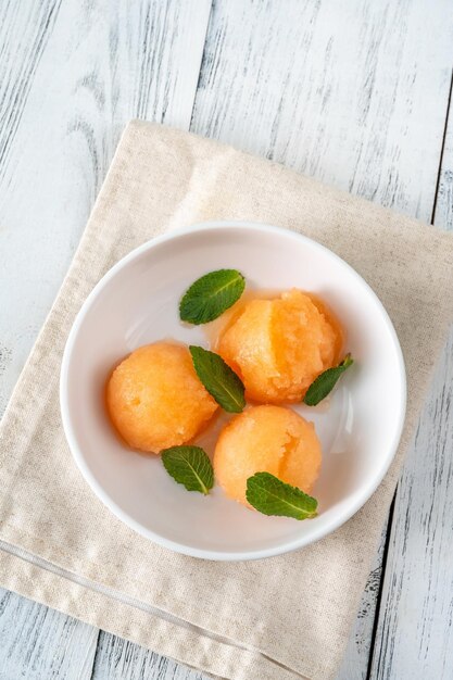 Cantaloupe-Minz-Sorbet mit frischen Minzblättern in der weißen Schale