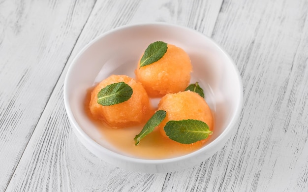 Cantaloupe-Minz-Sorbet mit frischen Minzblättern in der weißen Schale