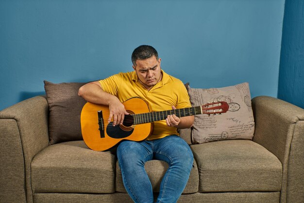 Cantando e tocando violão em casa em um sofá relaxado