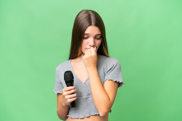 Foto cantante adolescente recogiendo un micrófono sobre un fondo aislado que tiene dudas