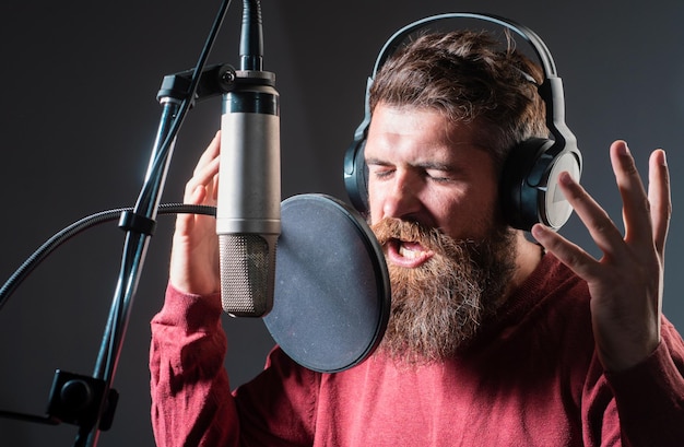 Cantante cantando una canción de grabación de rock en un estudio de música emocionado karaoke