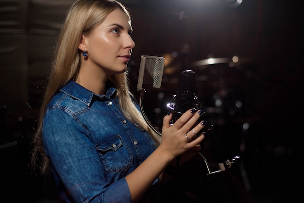 Cantante cantando una canción. Mujer actuando en un estudio de grabación