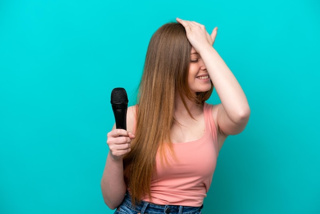 La cantante caucásica que toma un micrófono aislado de fondo azul se ha dado cuenta de algo y tiene la intención de encontrar la solución