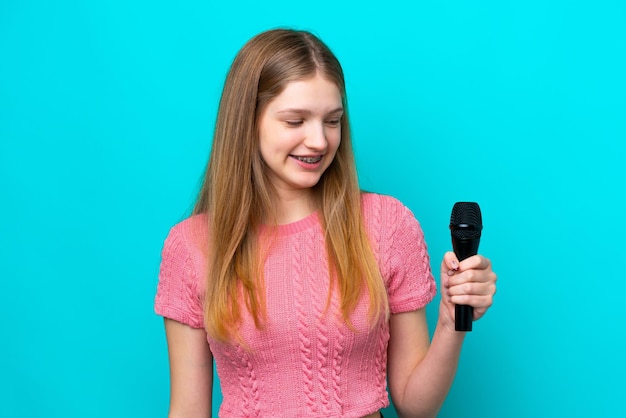 Cantante rusa recogiendo un micrófono aislado de fondo azul con expresión feliz