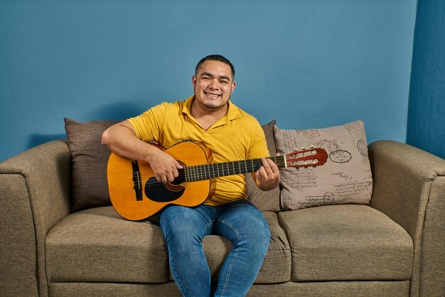 Cantar y tocar la guitarra en casa en un sofá relajado