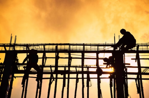 Foto canteiro de obras da silhueta com o trabalhador no por do sol.