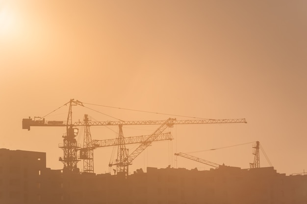 Canteiro de obras e guindastes ao nascer do sol