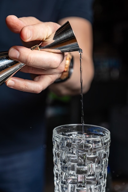 Foto un cantinero está sirviendo un cóctel de un vaso.