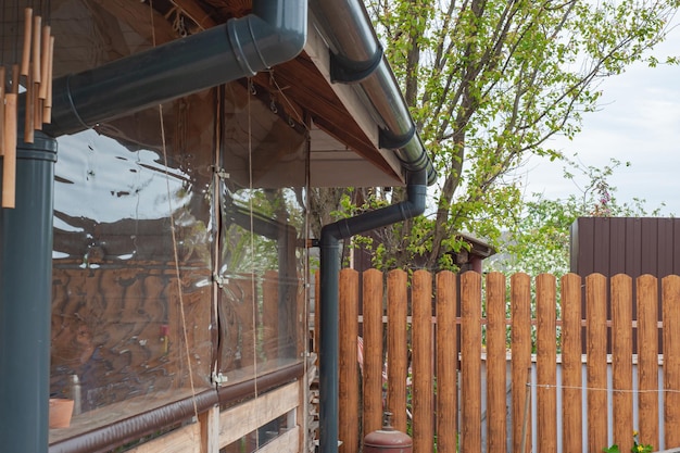 Canto da casa com novo telhado de telha metálica cinza e calha de chuva Sistema de calhas metálicas Calhas e tubos de drenagem Exterior