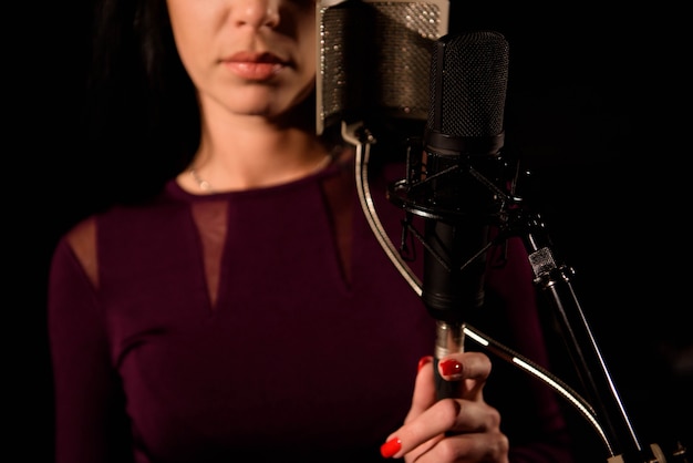 Foto cantora jovem na frente do microfone.