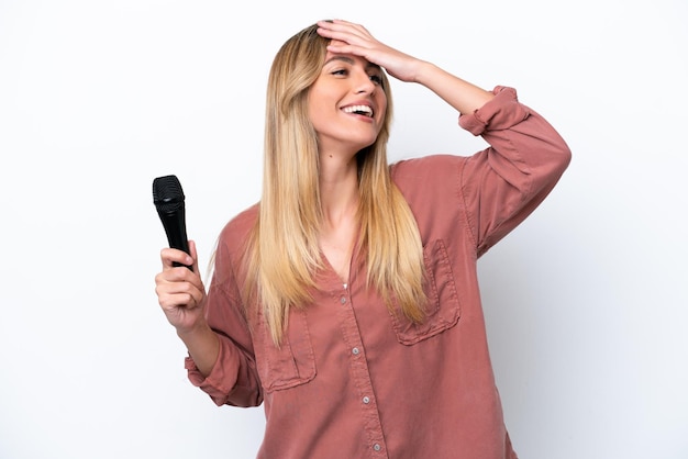 Cantora uruguaia pegando um microfone isolado no fundo branco sorrindo muito