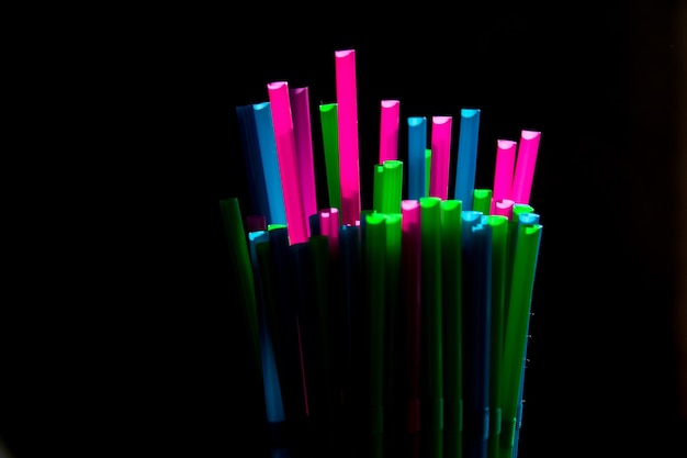 Canudos de plástico coloridos em fundo escuro plano leigo Ecologia conceito luz e sombra