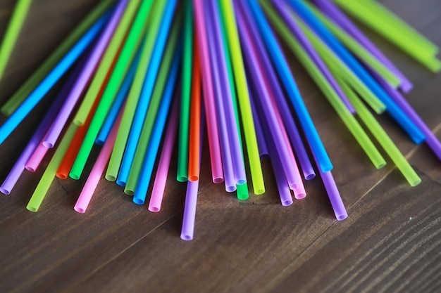 Canudos de plástico coloridos fecham-se como túbulos coloridos de fundo para suco e coquetéis na mesa de madeira preta