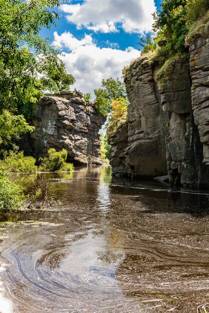 Canyon, zwischen dem ein Fluss gegen den blauen Himmel und grüne Bäume fließt