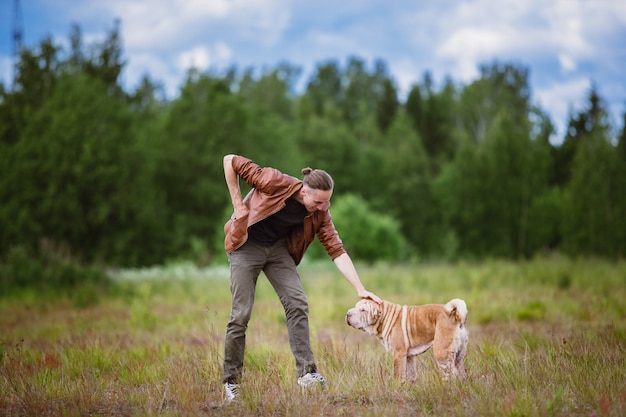 Cão da raça shar pei e um homem a passear