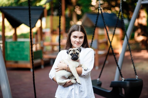 Cão e menina felizes A menina está brincando com um cachorro Jovem mulher andando com um cachorro pug no parque de verão Retrato de um pug Retrato de um lindo cachorrinho pug O cachorro está deitado no chão