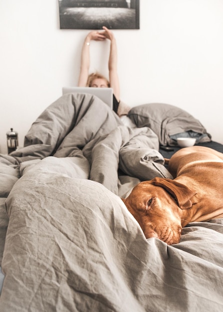 Foto cão e mulher a descansar na cama.