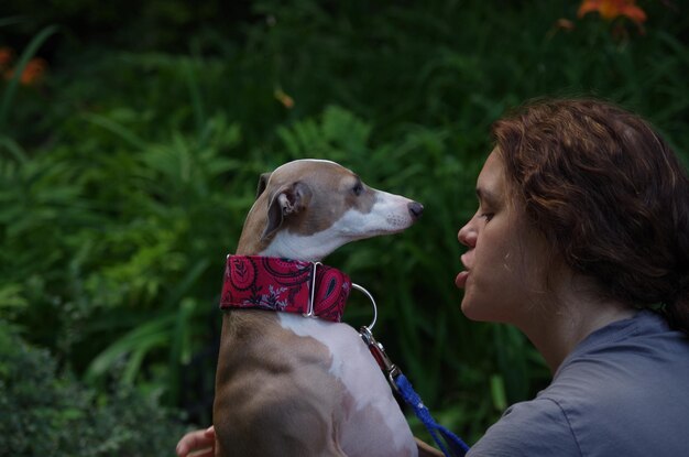 Cão olhando para a mulher contra as plantas