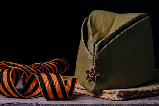 Cap mit roten Sternen Soldaten der Roten Armee ein altes zertrümmertes Buch und ein St. George Band Siegestag Feiertag