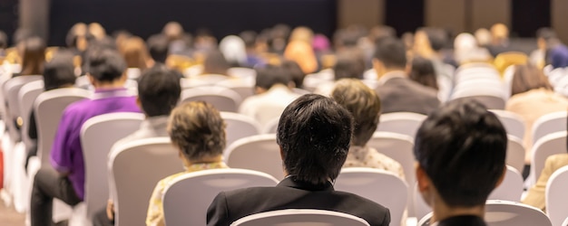 Capa da faixa de visão traseira do público ouvindo os palestrantes no palco na sala de conferências ou na reunião do seminário, negócios e educação sobre investimentos