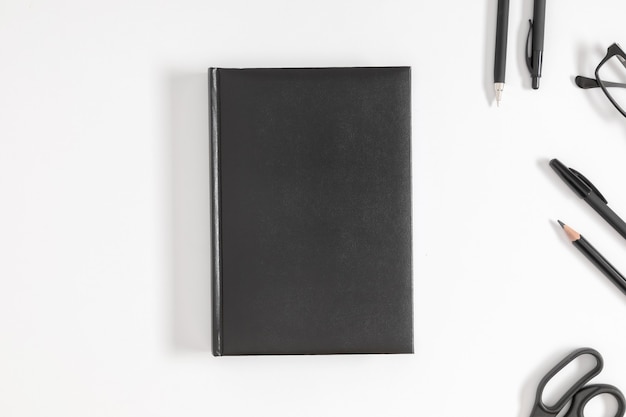 Capa de livro preta simulada e papelaria em fundo branco