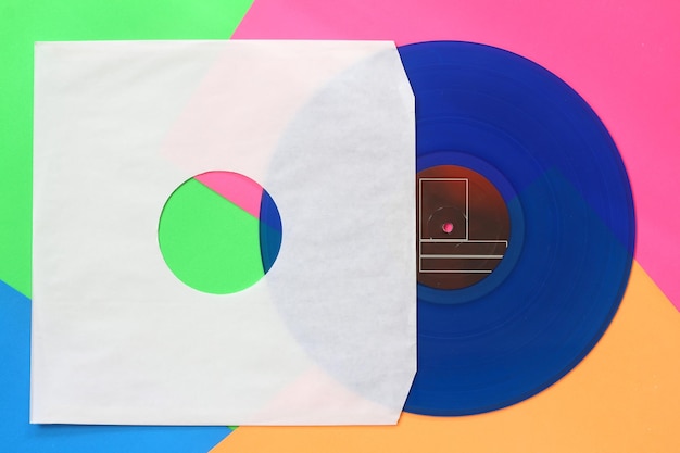 Foto capa de papel branco envelhecido e disco de vinil azul isolado em fundo colorido