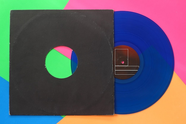 Capa de papel preto envelhecido e disco LP de vinil azul isolado em fundo colorido