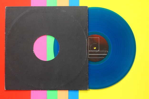 Capa de papel preto envelhecido e disco LP de vinil azul isolado em fundo colorido