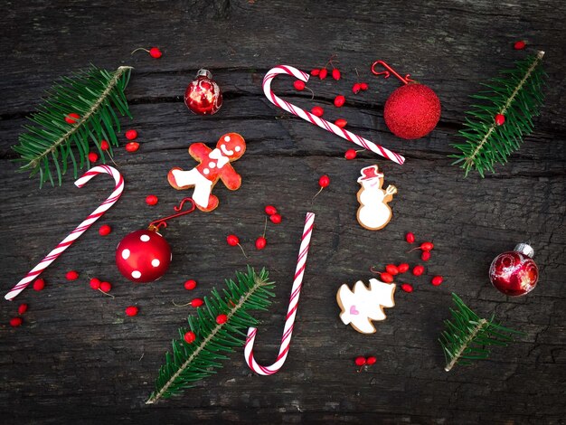 Una capa plana de decoraciones navideñas rojas y blancas que consisten en caramelos de caña de pan de jengibre y cinta roja