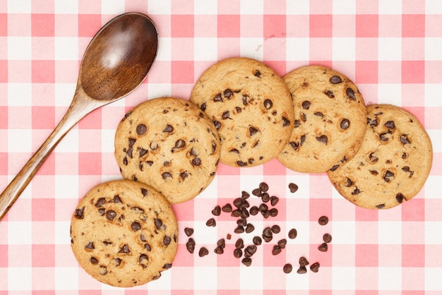 Una capa plana de dulces caseros, galletas de chocolate y cuchara en tela roja de gingham