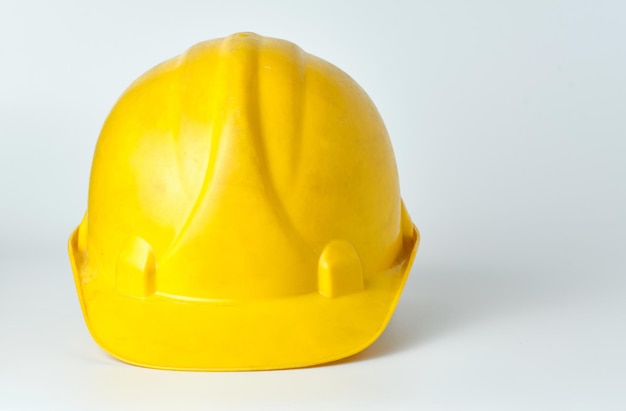 Capacete amarelo desgastado de um trabalhador da construção civil no fundo branco