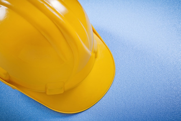 Capacete de segurança amarelo no conceito de construção de superfície azul.