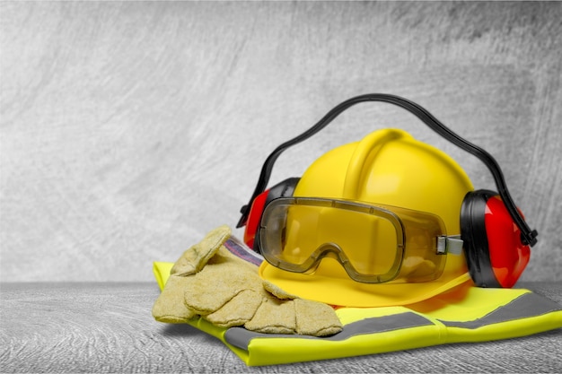 Capacete de segurança com fones de ouvido e óculos de proteção em fundo de construção