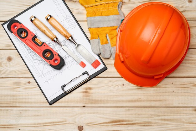 Capacete de segurança de ferramentas de trabalhador da construção civil e cinzel na vista superior de madeira