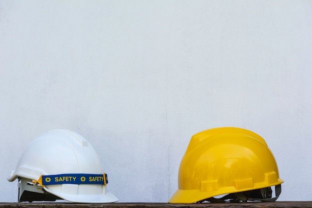 Capacete de segurança do capacete da construção, o amarelo e o branco na tabela de madeira.