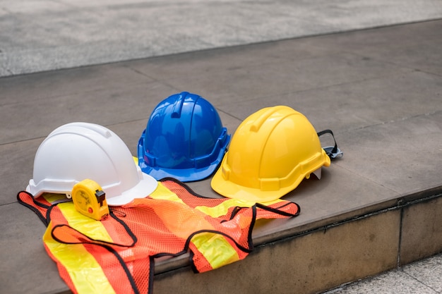 Capacete de segurança duro branco, azul, amarelo no colete com fita métrica