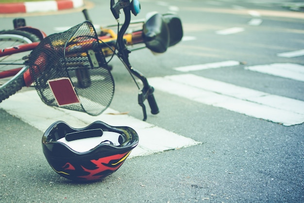 Capacete e bicicleta caídos na estrada em uma faixa de pedestres, após acidente