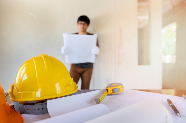 Capacete e blueprint na mesa na frente do engenheiro ou arquiteto.