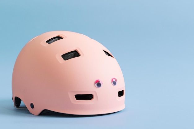 Capacete rosa com olhos engraçados de boneca sobre fundo azul Proteção de segurança para atividades ao ar livre da criança