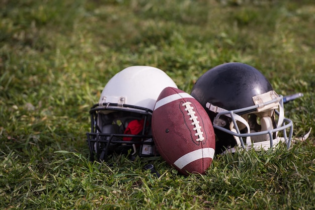 Capacetes de futebol americano e bola deitada no campo