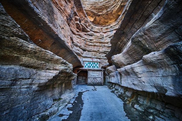 Capas de acantilados a través del cañón con camino pavimentado que conduce a la entrada de la cueva