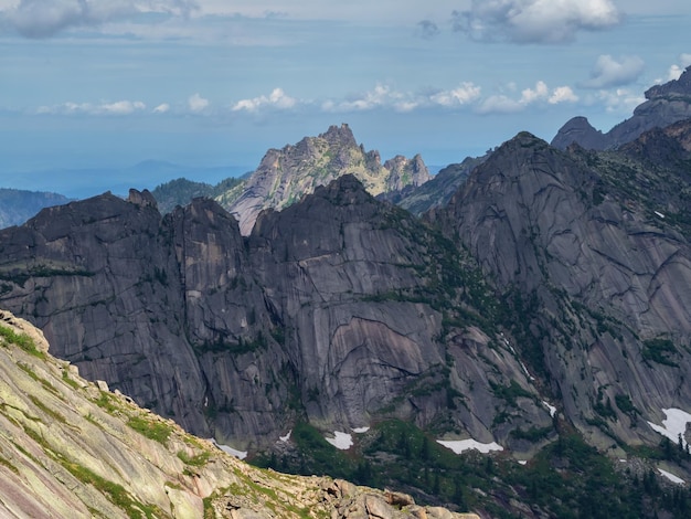 Capas montañosas textura del terreno Colorido paisaje matutino soleado con siluetas de grandes montañas rocosas La luz del sol se desliza a lo largo de las laderas de majestuosas montañas altas y afiladas desde cada lado