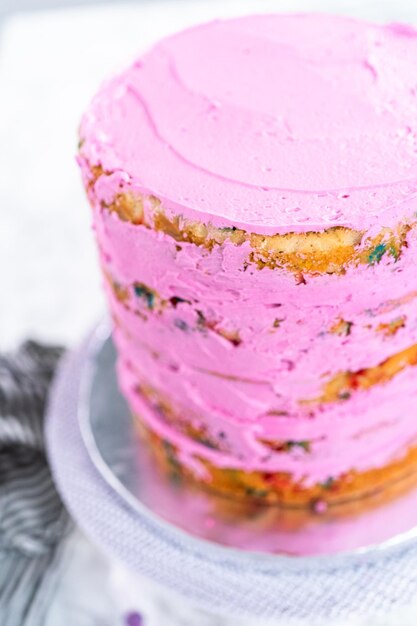 Capas de pastel Funfetti con glaseado de crema de mantequilla rosa.