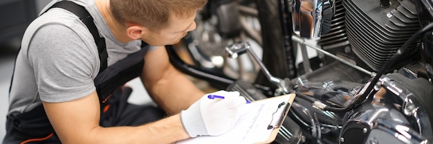 Capataz en el centro de reparación de servicio diagnostica piezas en motocicleta